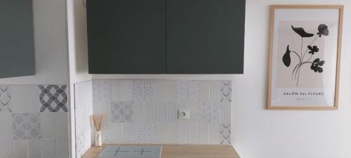 cocina con armario negro y azulejos blancos en Home with a view, appartement avec vue panoramique sur la mer, en Ouistreham