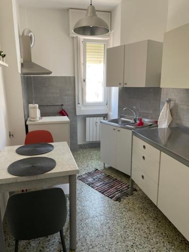 cocina con armarios blancos, mesa y fregadero en CASA DENDI, en Trieste