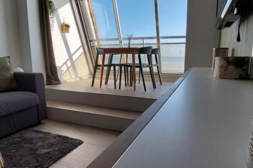 sala de estar con mesa y sillas frente a una ventana en Home with a view, appartement avec vue panoramique sur la mer, en Ouistreham