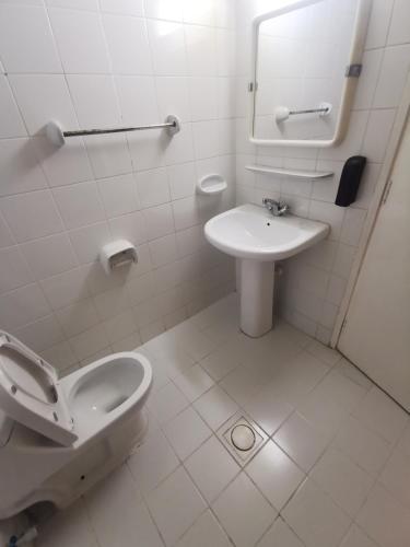 a white bathroom with a toilet and a sink at Cloud9 Premium Hostel in Dubai