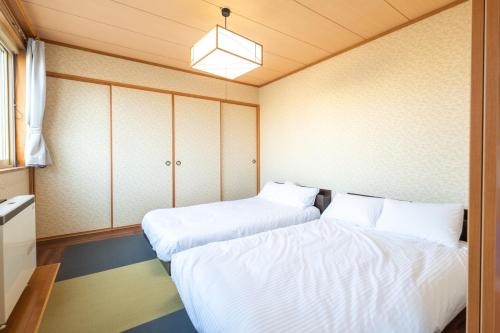 2 Betten in einem kleinen Zimmer mit weißer Bettwäsche in der Unterkunft Ezo Fujiya Niseko House - Vacation STAY 14767 in Kutchan