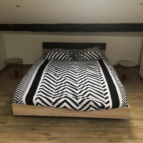 - un lit avec une couette en noir et blanc dans l'établissement Givors Centre Duplex meublé, à Givors