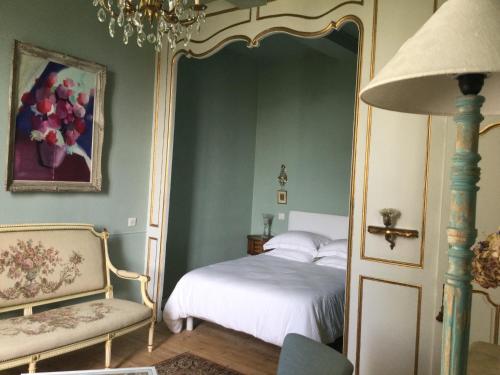 a bedroom with a bed and a chair at L’orangerie du Général in Saint-Jean-dʼAngély