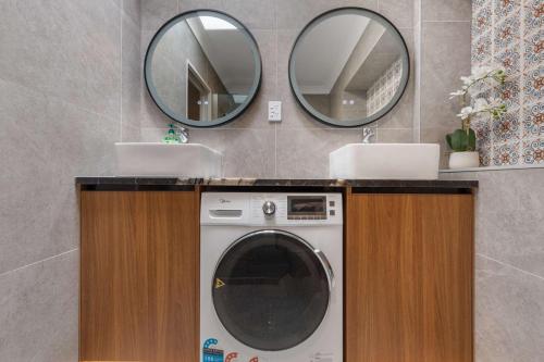 a bathroom with a washing machine and two mirrors at Lakefront Getaway in Rotorua in Rotorua