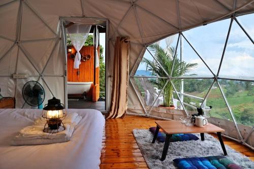 a bedroom with a tent with a tub and a table at มิด้าโฮมสเตย์ม่อนแจ่ม in Mon Jam