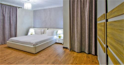 a bedroom with a white bed and wooden floors at Ocean Blue Apartments in Cairo