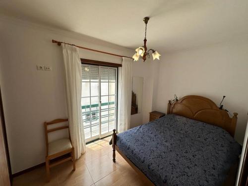 Un dormitorio con una cama y una ventana y una silla. en 100 Meters from the Beach! Rua da Regeneração Nazaré, en Nazaré
