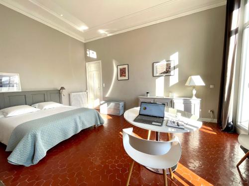 a bedroom with a bed and a desk with a laptop at Maison Dormoy in Marseille