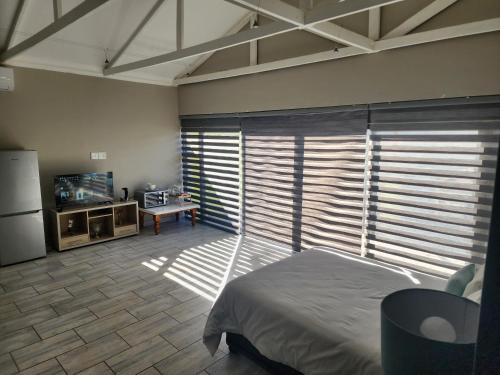 a bedroom with a bed and a refrigerator and a table at Bayswater Guest Rooms in Bloemfontein