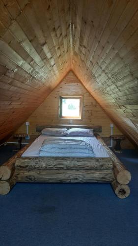 a bed in a wooden cabin with a window at Drinska Ljepotica in Bijeljina