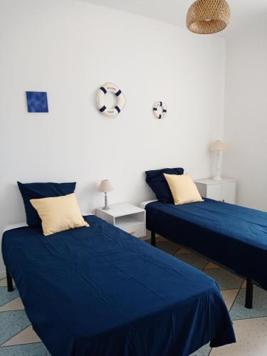 - 2 lits dans une chambre avec des draps et des oreillers bleus dans l'établissement Les Abricots, à Tarascon