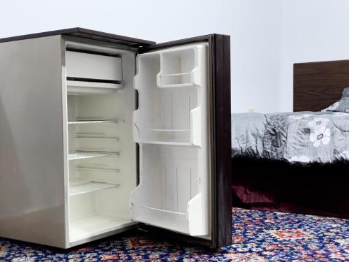 a white refrigerator with its door open next to a bed at west view hostel in ‘Ayn Amūn
