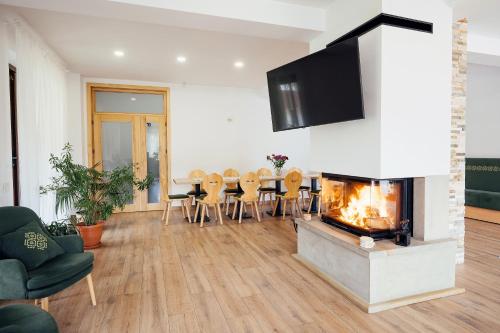 a living room with a fireplace and a table and chairs at Blumenhof Bucovina in Voronet