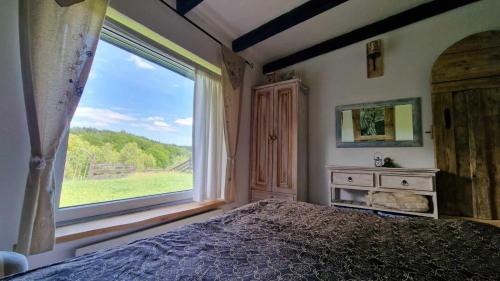 a bedroom with a bed and a large window at Domki w Lipowej Dolinie in Huta Górna