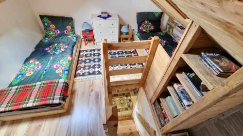 an attic room with two beds and a book shelf at Domki w Lipowej Dolinie in Huta Górna