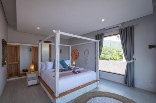 a bedroom with a canopy bed with a large window at Kamana Beach House in Mangsit