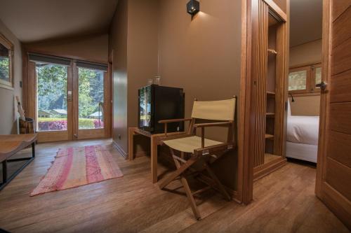 Habitación con escritorio, TV y silla. en Las Qolqas EcoResort Ollantaytambo, en Ollantaytambo