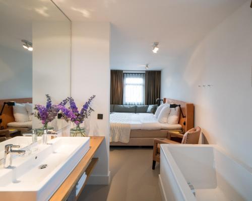 a bathroom with a sink and a bedroom with a bed at Relaîs & Châteaux Bij Jef in Den Hoorn