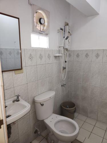 a white bathroom with a toilet and a sink at Country Sampler Inn in Tagaytay