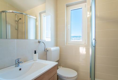 ein Bad mit einem Waschbecken, einem WC und einem Fenster in der Unterkunft Villa Sortis in Pag
