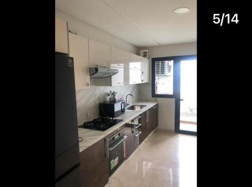 a kitchen with white cabinets and a sink and a refrigerator at excelente apartamento en sky 17 , tanger 7 in Tangier