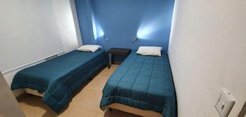 Cette chambre bleue comprend 2 lits et une table. dans l'établissement Departamentos Serena, à Puerto Iguazú