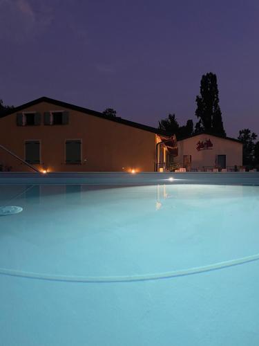 a large swimming pool in front of a house at night at Corte Attilea in Valeggio sul Mincio