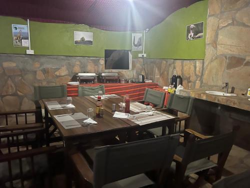 un restaurante con mesa de madera, sillas y barra en Sunset camp en Narok