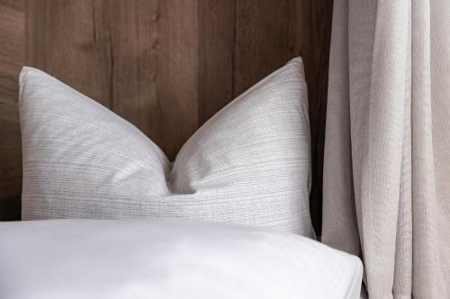 a bed with white pillows next to a wooden wall at Bergmadl Apartments in Neustift im Stubaital