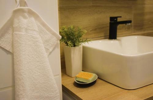 La salle de bains est pourvue d'un lavabo et d'une serviette blanche. dans l'établissement Shine Apartman, à Szentgotthárd