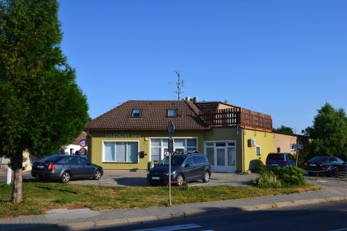 a yellow house with two cars parked in front of it at Apartmány Podyjí in Znojmo