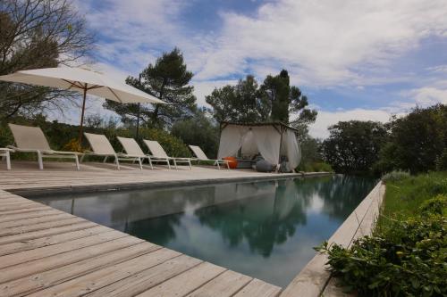 une piscine avec des chaises longues et un parasol dans l'établissement Bien Loin d'Ici Spa B&B, à Nîmes