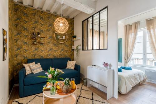 ein Wohnzimmer mit einem blauen Sofa und einem Bett in der Unterkunft Ulysse - Charmant T2 dans le Centre de Pont-Audemer in Pont-Audemer