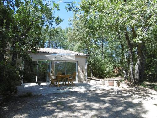 eine Terrasse mit einem Tisch und einem Sonnenschirm in der Unterkunft Pied à terre au coeur du Luberon, Provence in Viens