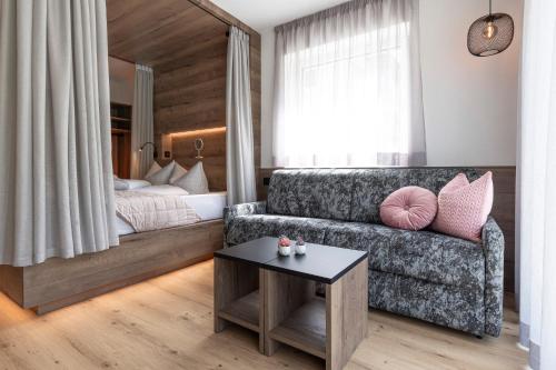 a living room with a couch and a bed at Bergmadl Apartments in Neustift im Stubaital
