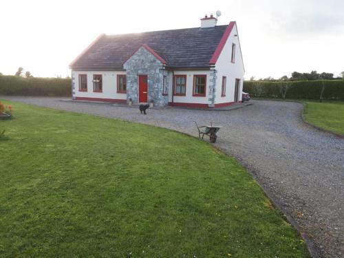 a small white house with a bench in front of it at Ballytigue House in Droíchead an Chláir