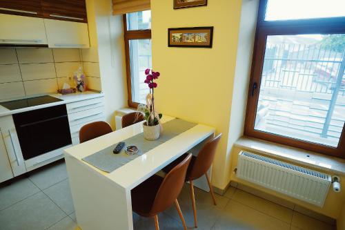 a kitchen with a table with a vase of flowers on it at Magio Apartments in Turda
