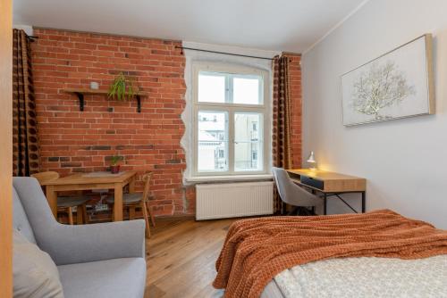sypialnia z ceglaną ścianą, łóżkiem i stołem w obiekcie Rüütli Apartments in Tartu Old Town w mieście Tartu