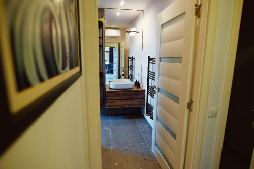a hallway leading to a bathroom with a sink at Magio Apartments in Turda
