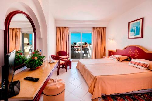 a hotel room with a large bed and a table at Les Quatre Saisons Ex Baya Beach in Djerba