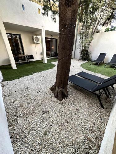 un banc noir à côté d'un arbre à côté d'une maison dans l'établissement BDSM TanTra Love Room & SPA, à Miramas