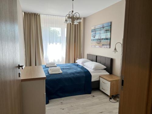 a bedroom with a bed with blue sheets and a window at Apartament BARI in Świnoujście