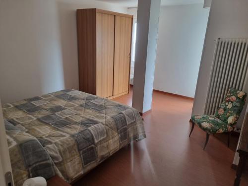 a bedroom with a bed and a chair and a cabinet at La Casa di Paolo, Pieve di Cadore centro in Pieve di Cadore