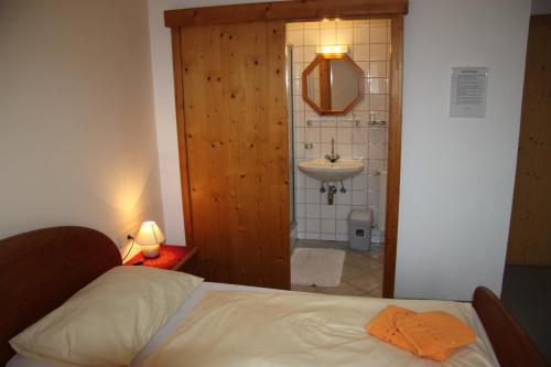 a bedroom with a bed and a bathroom with a sink at Pension Merkinger in Behamberg