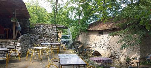 a patio with tables and chairs next to a stone building at Studio Bane in Soko Banja
