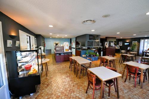 a restaurant with tables and chairs and a refrigerator at Kyriad Tarbes Odos in Odos