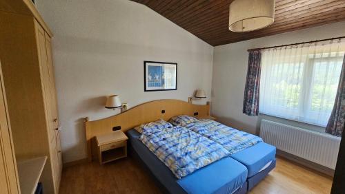 a bedroom with a bed with a blue blanket on it at Landhaus Wald und See Nr. 35 in Biersdorf