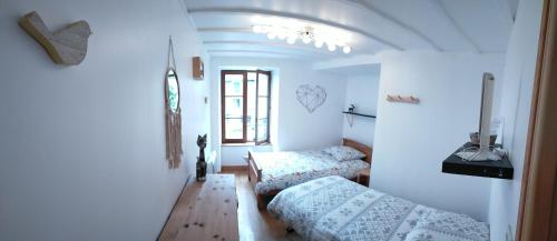 a white room with two beds and a window at Maison au coeur du Sancy à la Tour d'Auvergne in La Tour-dʼAuvergne