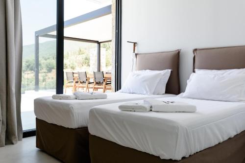 two twin beds in a room with a large window at Mandevilla Hillside Luxury Villas in Agios Nikitas
