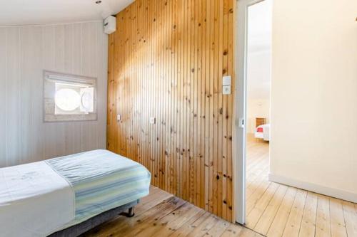 une chambre avec un lit et un mur en bois dans l'établissement Meublé de tourisme courts séjours déplacements professionnels, à Ruelle-sur-Touvre